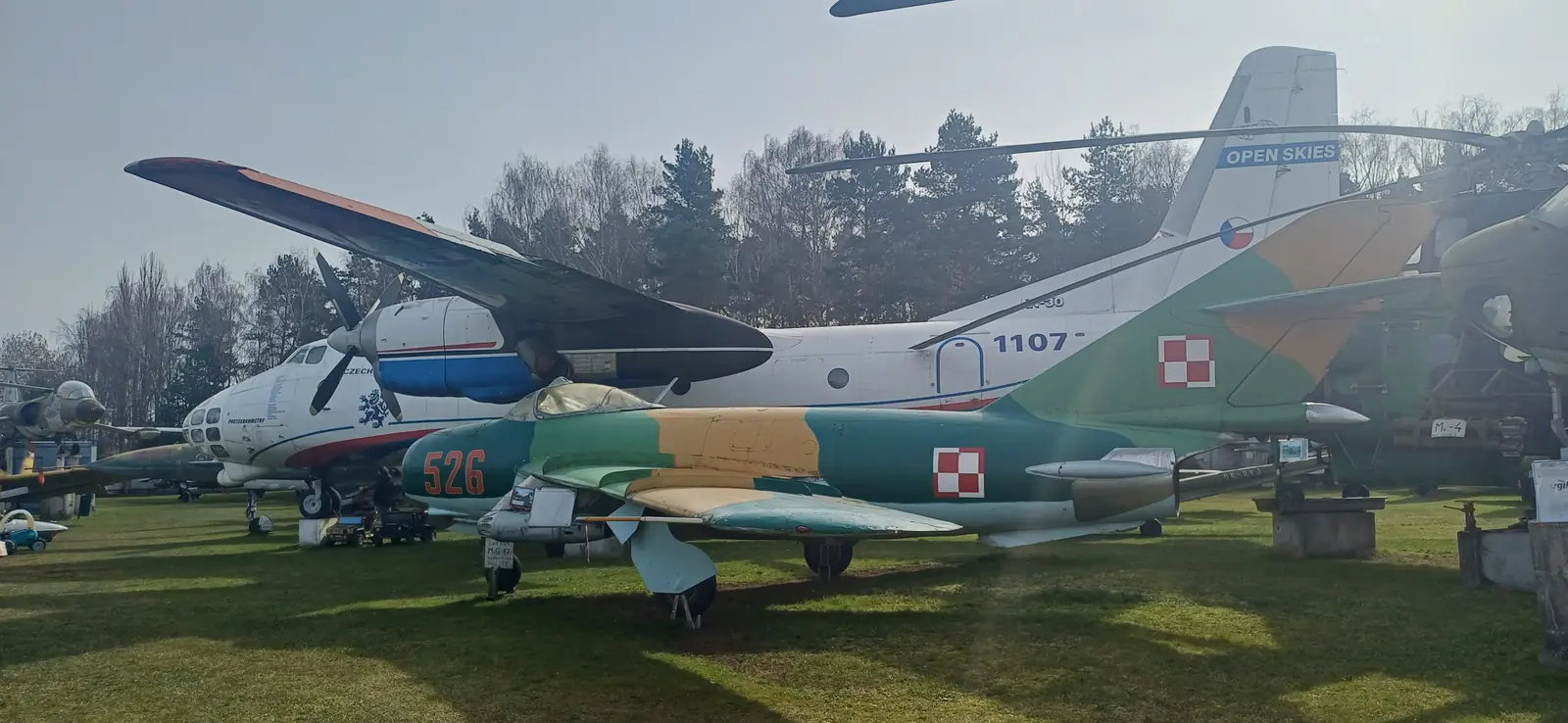 Letadla na louce Air Parku Zruč, vpředu stíhačka v polských barvách a za ní An-30
