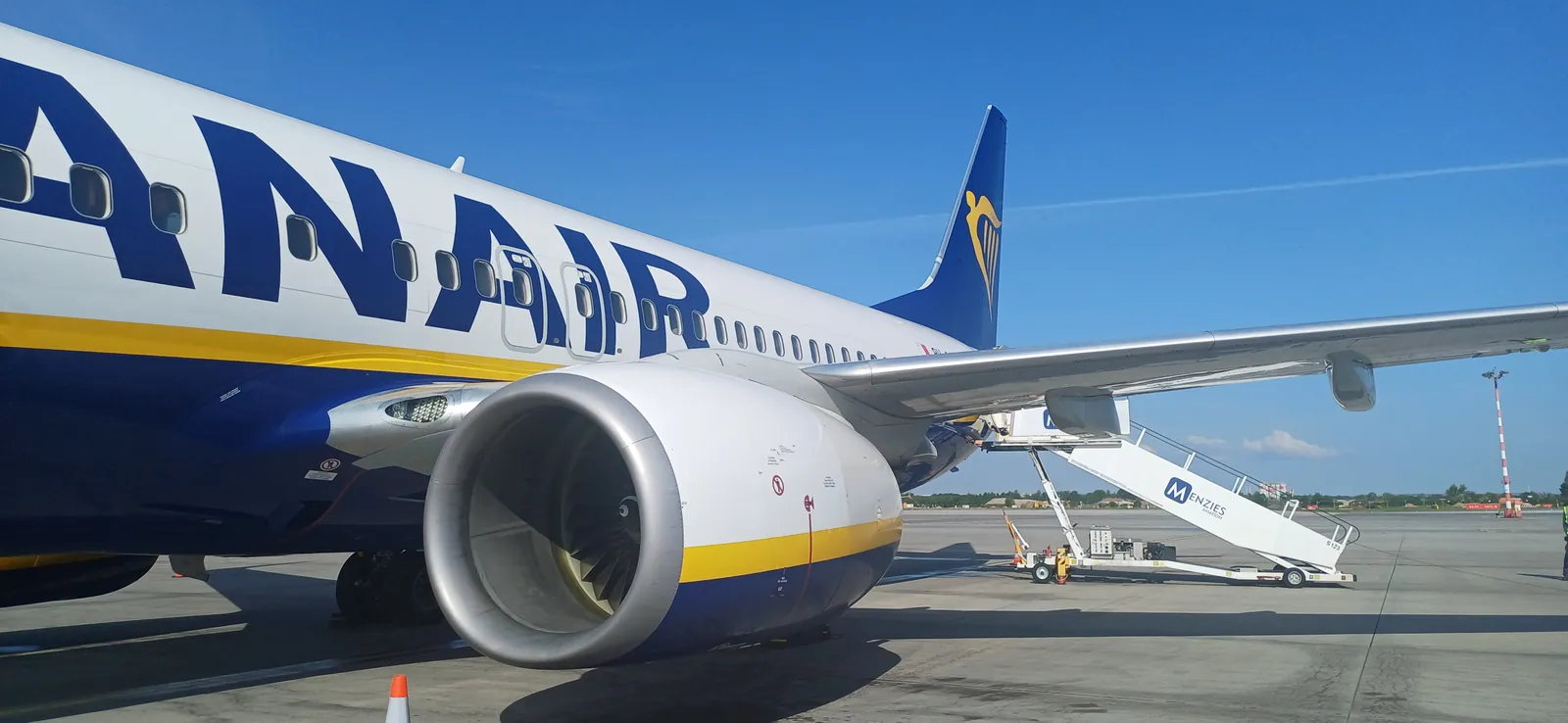 Boeing 737 společnosti Ryanair na odbavovací ploše, u zadních dveří stojí nástupní schody