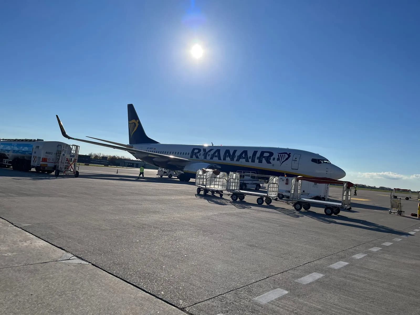 Boeing 737 Ryanairu na ploše, před ním stojí vozíky se zavazadly